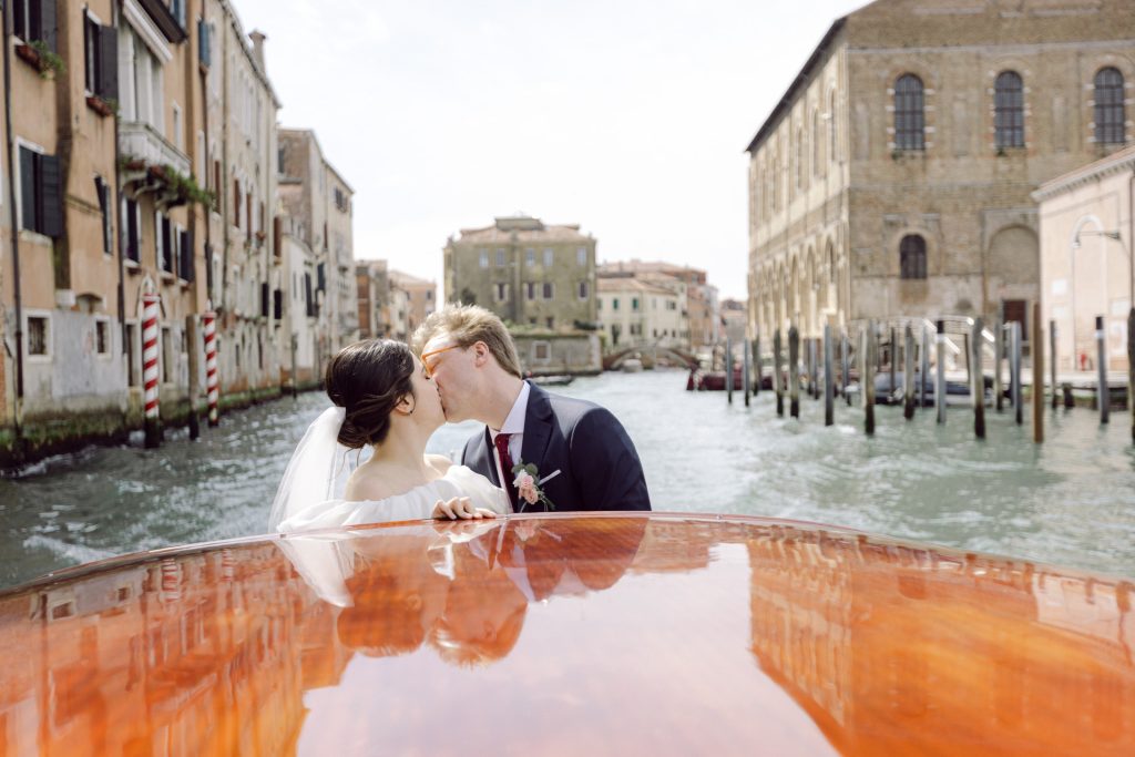 Couple kissing on a water taxi boat at their intimate wedding in Venice in March
