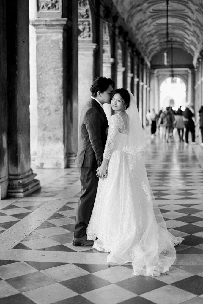 Couple in wedding attire under the porticos in Piazza San Marco, Venice