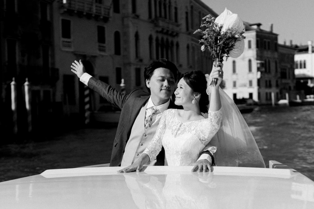 Happy Couple in wedding attire on a water taxi on the Grand Canal in Venice 