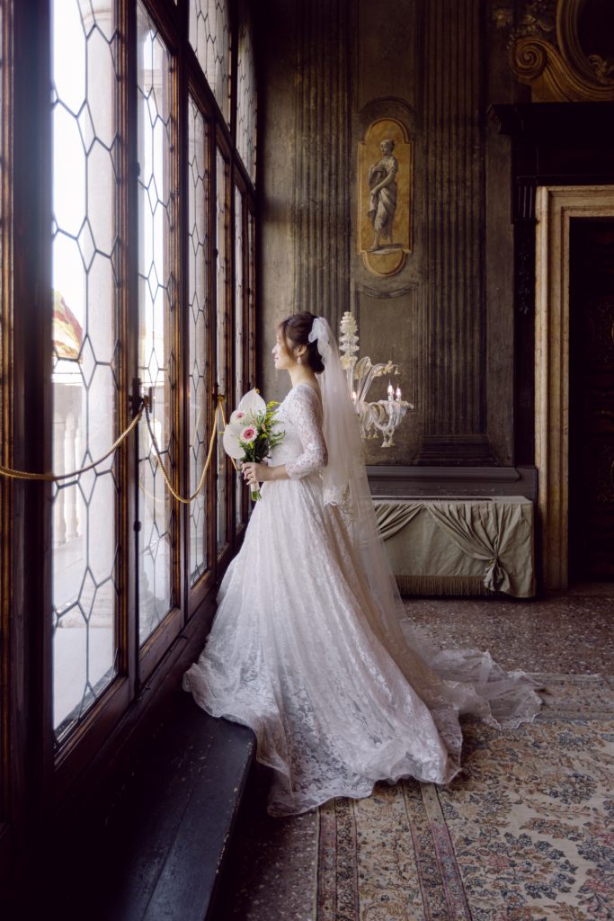 Bride looking outside the windows of Ca' Sagredo hotel, Venice
