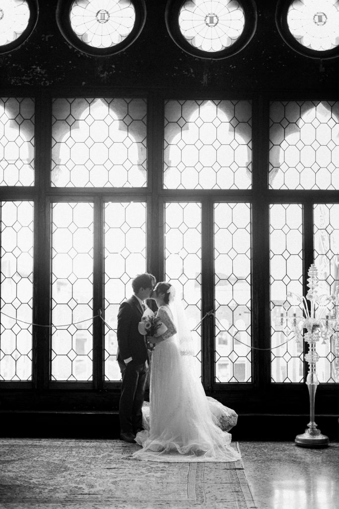 Bride and groom in front of the majestic windows of Ca' Sagredo hotel, Venice