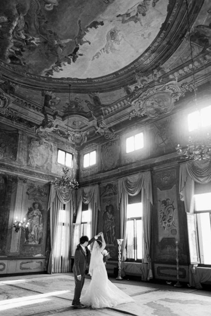 Bride in her wedding gown with her partner among the frescoes of Ca' Sagredo hotel, Venice