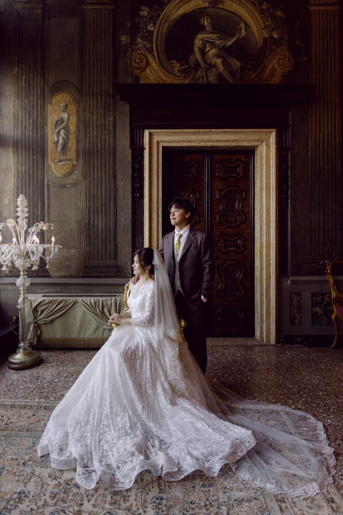 Bride in her wedding gown with her husband among the frescoes of Ca' Sagredo hotel, Venice