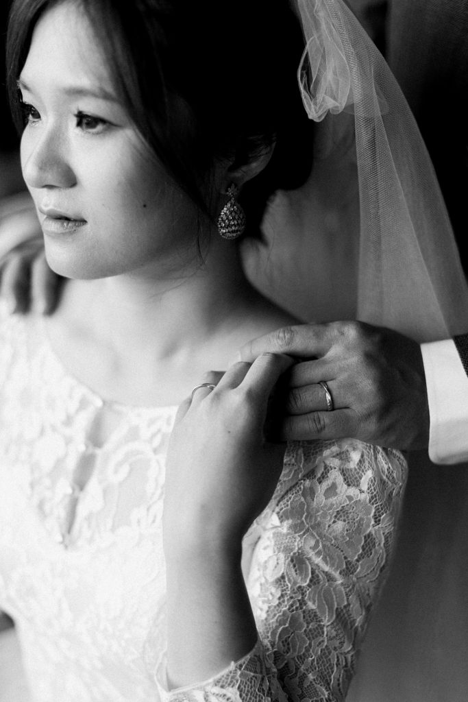Bride in her wedding gown with her partner touching hands among the frescoes of Ca' Sagredo hotel, Venice